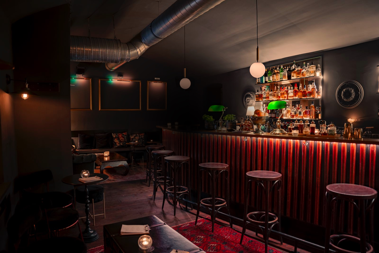 The bar at Saint George, warm light over the bottles and red velvet bar front