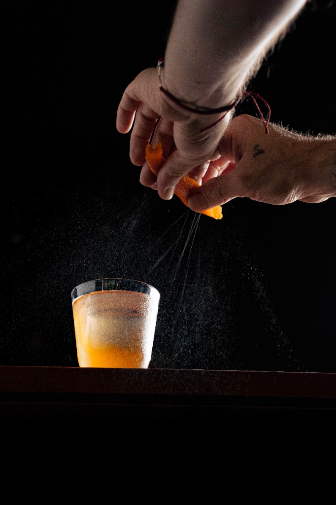 Expressing an orange peel over a cocktail at Saint George